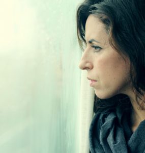 CLose up of woman looking out of the window looking sad