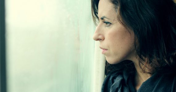 CLose up of woman looking out of the window looking sad