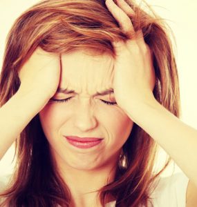 A woman holding her head in pain representing a migraine