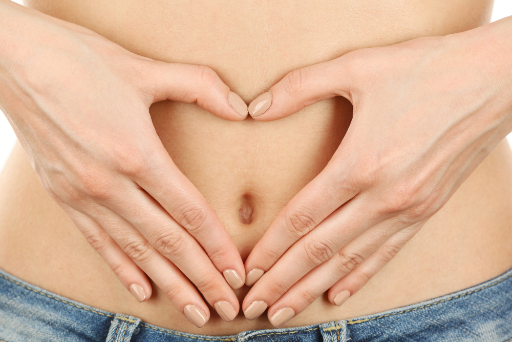 Woman making a heart shape wiht her hands over her tummy to represent gut health