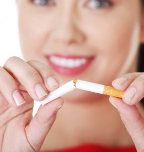 A woman breaking a cigarette in half to represent giving up smoking