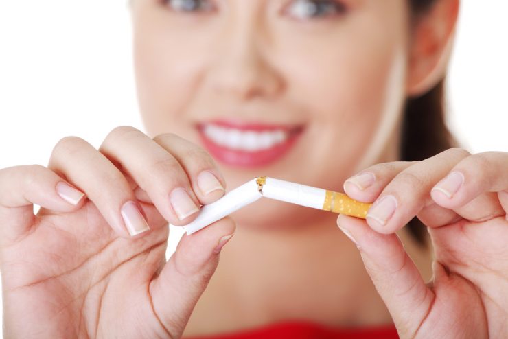 A woman breaking a cigarette in half to represent giving up smoking