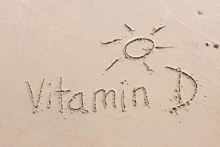 Vitamin D and a sunshine written into the sand on beach