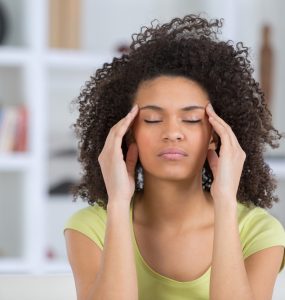 Woman with anxiety with eyes closed and touching hands to temples