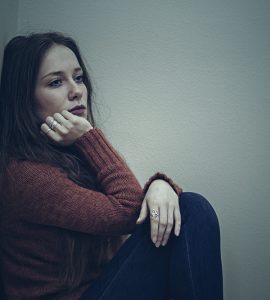 Woman sitting on floor looking sad demonstrating low mood