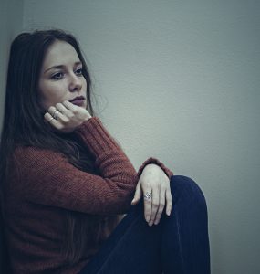 Woman sitting on floor looking sad demonstrating low mood