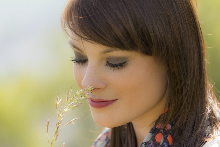 Close up of woman smelling wild flowers to show hay fever