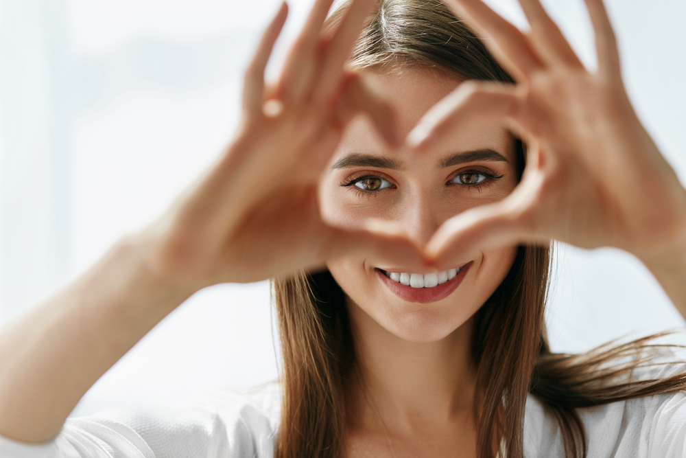 Woman using hands to make a heart showcasing her eyes to represent good eye health