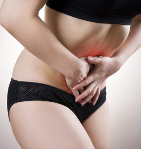 Woman holding lower abdomen to represent cystitis