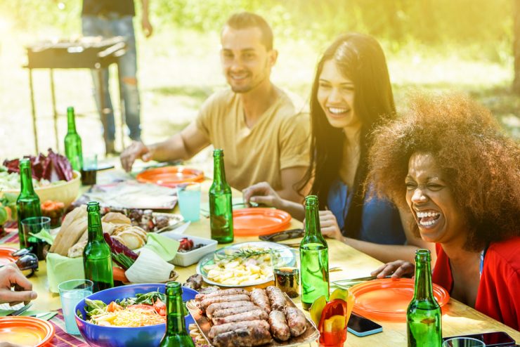 A group of people have fun at a bbq eating outdoors
