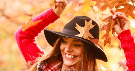 Close up of happy woman in autumn with falling leaves