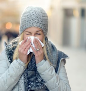 Woman with cold blowing her nose