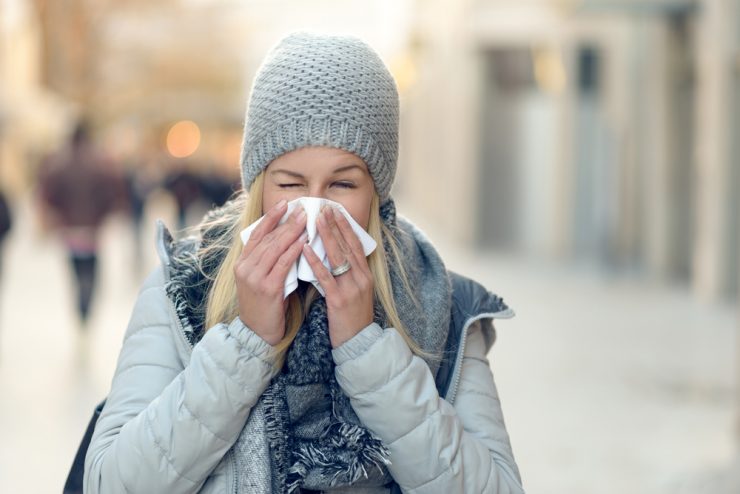 Woman with cold blowing her nose