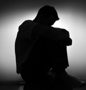 BLack and white picture of a man with depression and low mood, with his head in his hands