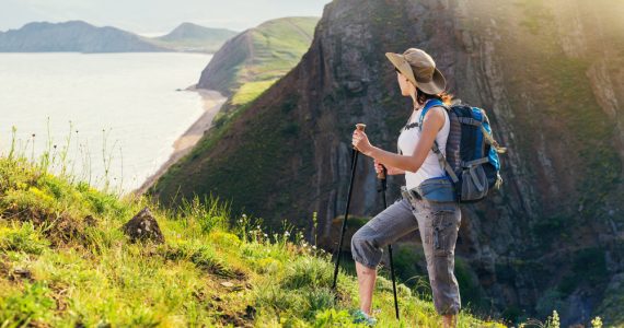 A woman hiking outdoors overlooking a sea cliff