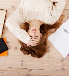 Woman lying on floor surrounded by work representing stress