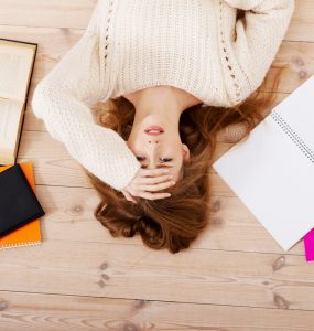 Woman lying on floor surrounded by work representing stress