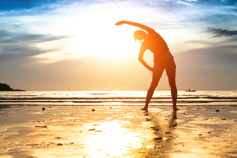 Woman working out outdoors stretching by the sea