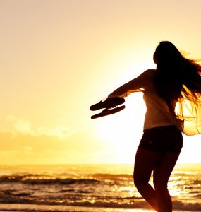 Woman dacning on beach at sunset on holiday