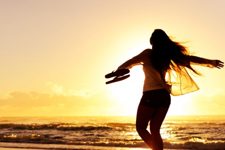 Woman dacning on beach at sunset on holiday