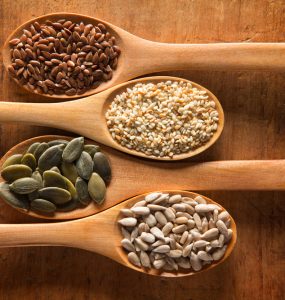A range of seeds on individual wooden spoons