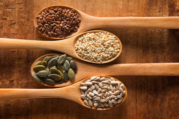 A range of seeds on individual wooden spoons