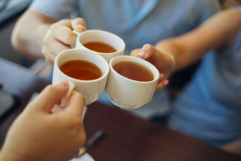 Close up of tea cups being clinked together