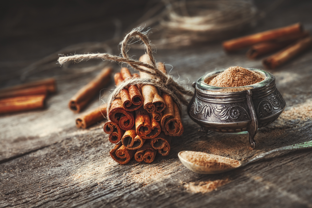 A bound pile of cinnamon sticks and pot of ground cinnamon