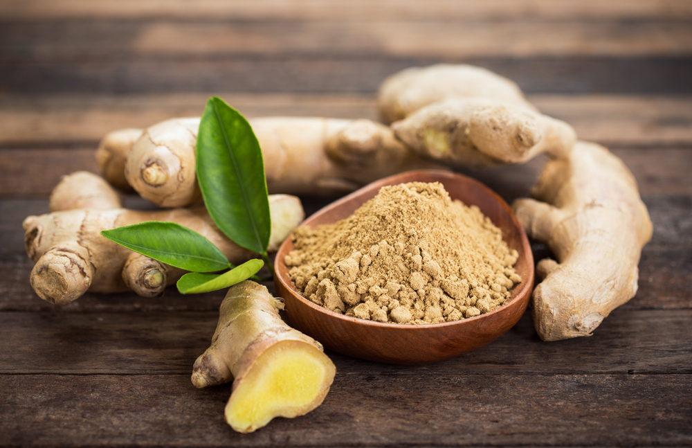 Ginger root and ground ginger in a wooden bowl