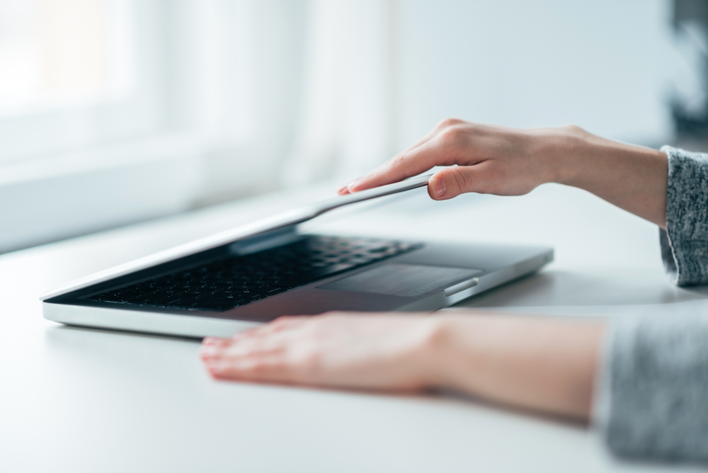 Close up of woman closing laptop to represent ending the working day