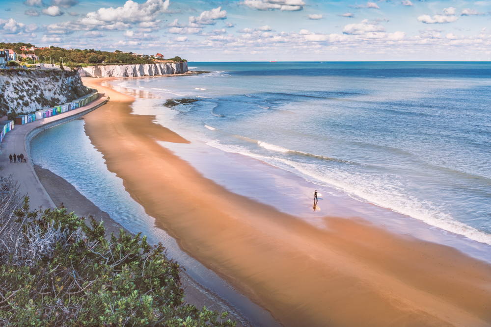 Beach landscape in the UK with woman walking along the sea front