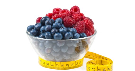 A bowl of fruit with a measuring tape around it to represent weight management