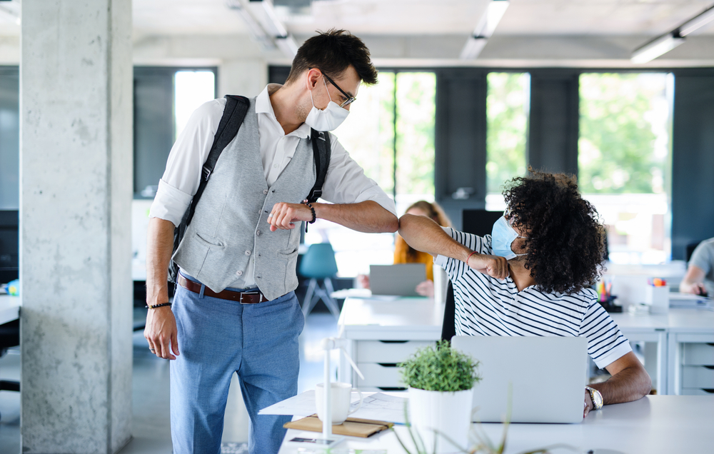 Coleagues elbow bumping in the office to say Hi