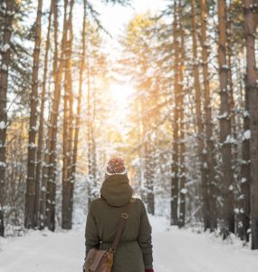 Woman taking a winter walk in snowy woodland