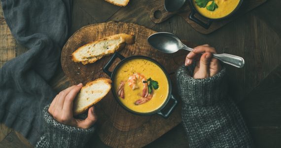 Close up of woman in cosy jumper eating soup