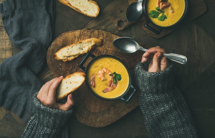 Close up of woman in cosy jumper eating soup