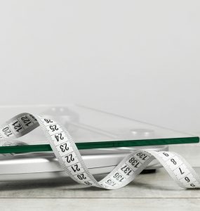 A measuring tape and scales to represent weight management
