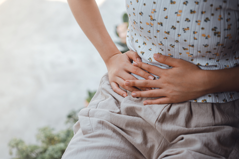 Close up of woman holding her tummmy to represent indigestion