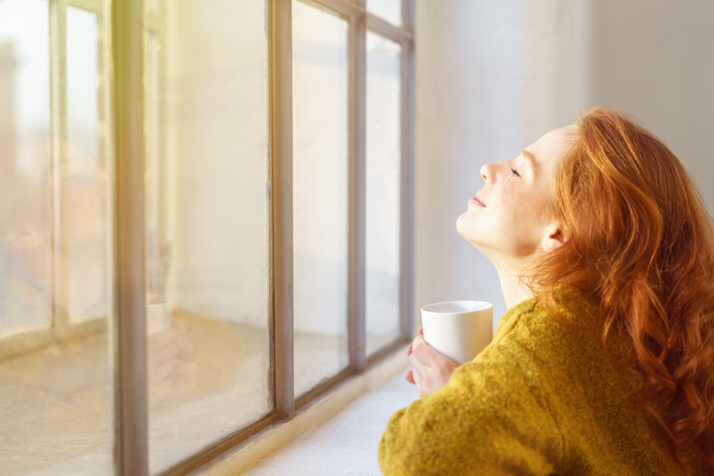 Woman looking out of a sunny window