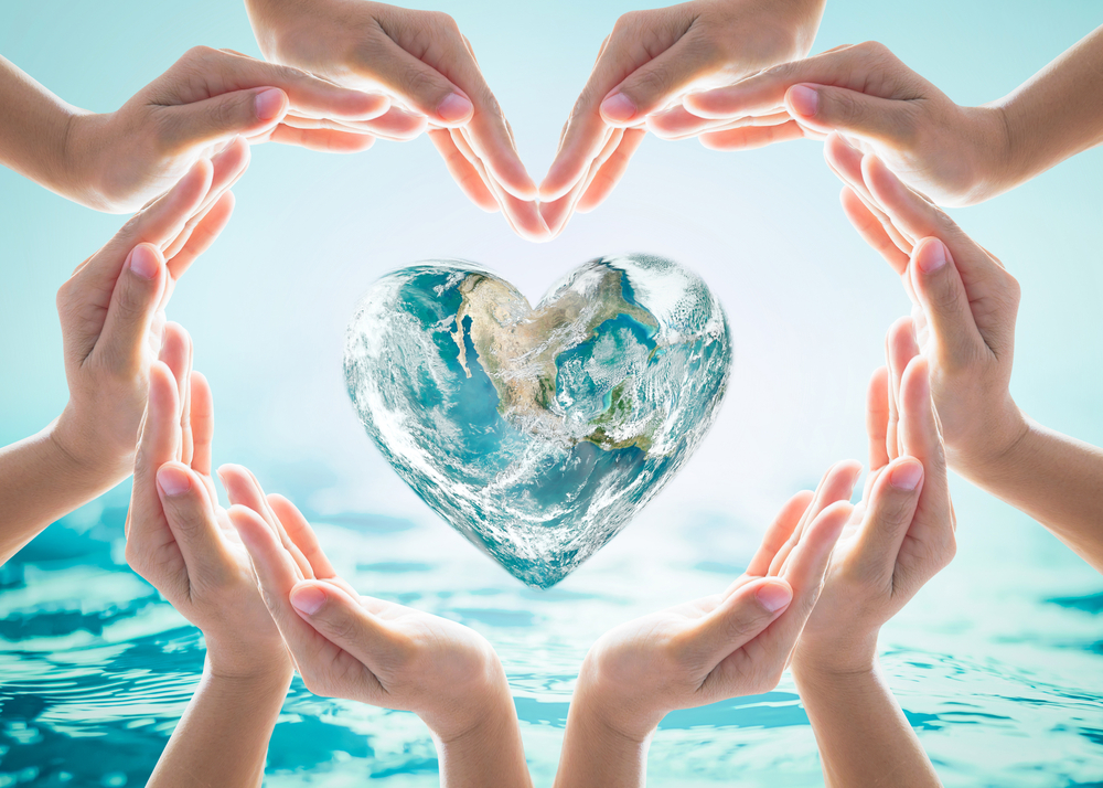 Hands forming a heart shape around a heart shaped world