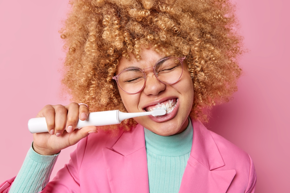 Woman brushing her teeth with an electric toothbrush